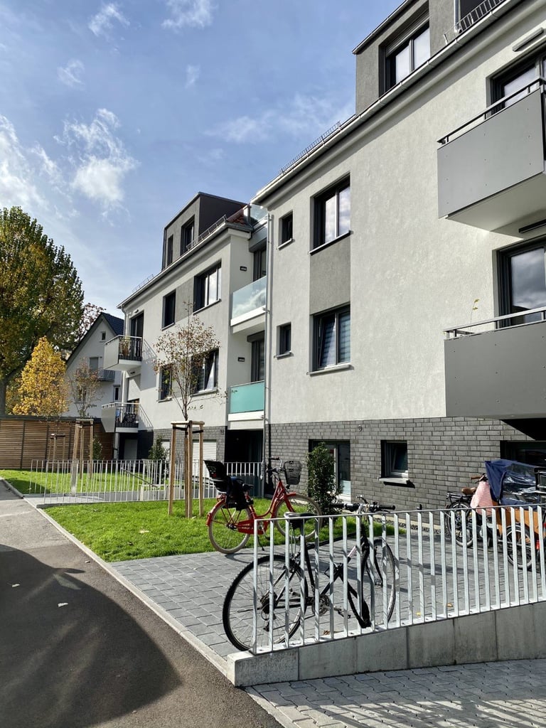 Modern residential building with bicycles parked in white rack on green lawn area